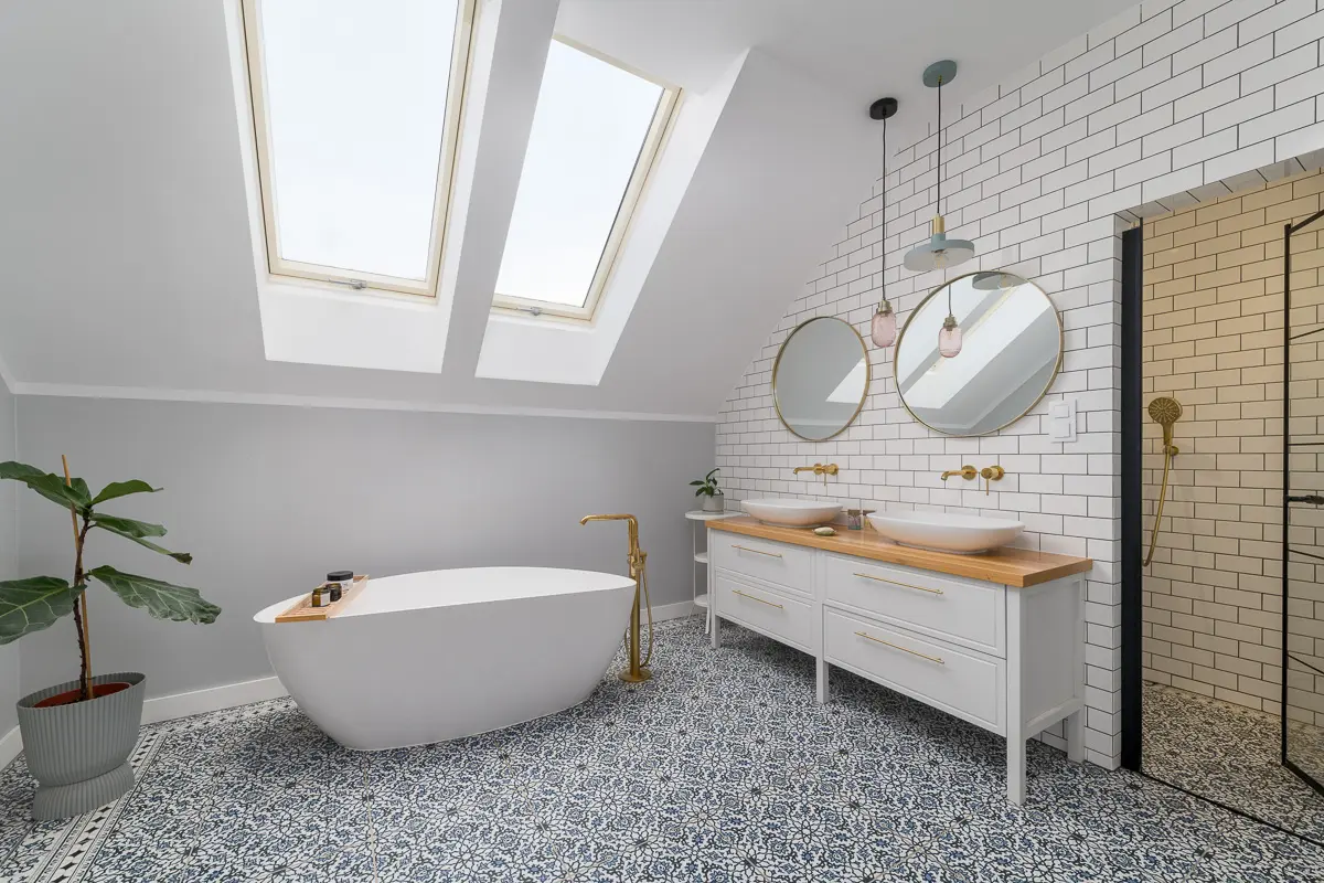 Widna łazienka na poddaszu z wolnostojącą wanną i błękitną mozaiką na podłodze.